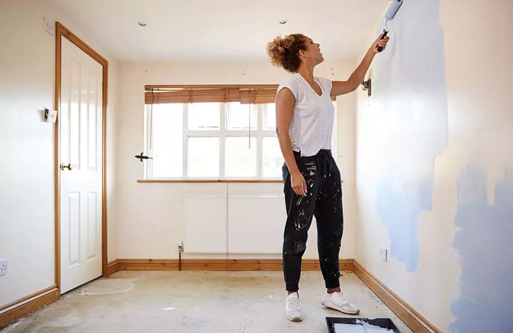 Woman-decorating-room-in-new-home-painting-wall